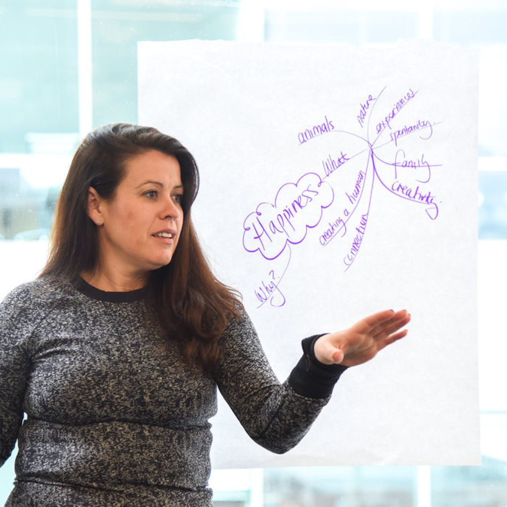 Woman speaking in front of a whiteboard.