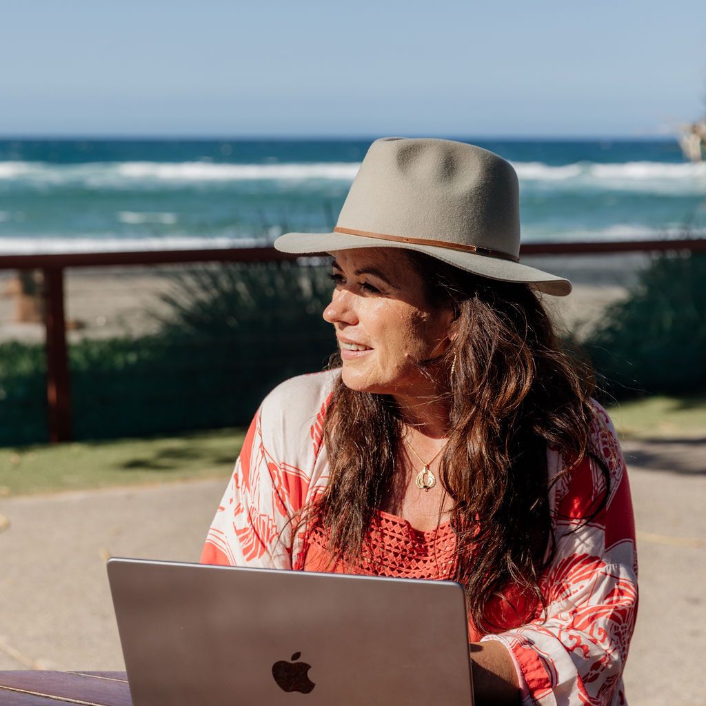 Woman working on her laptop by the beach.