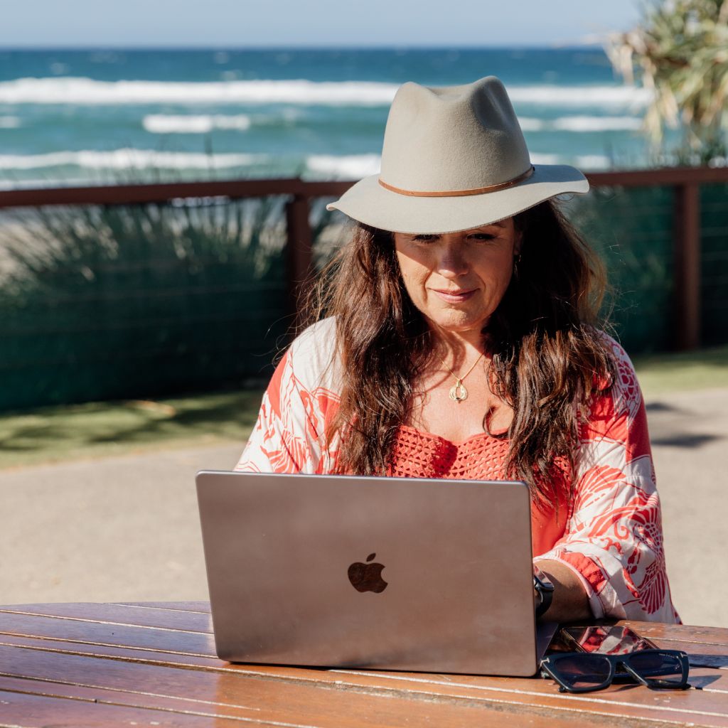 Woman is working on her laptop by the beach.