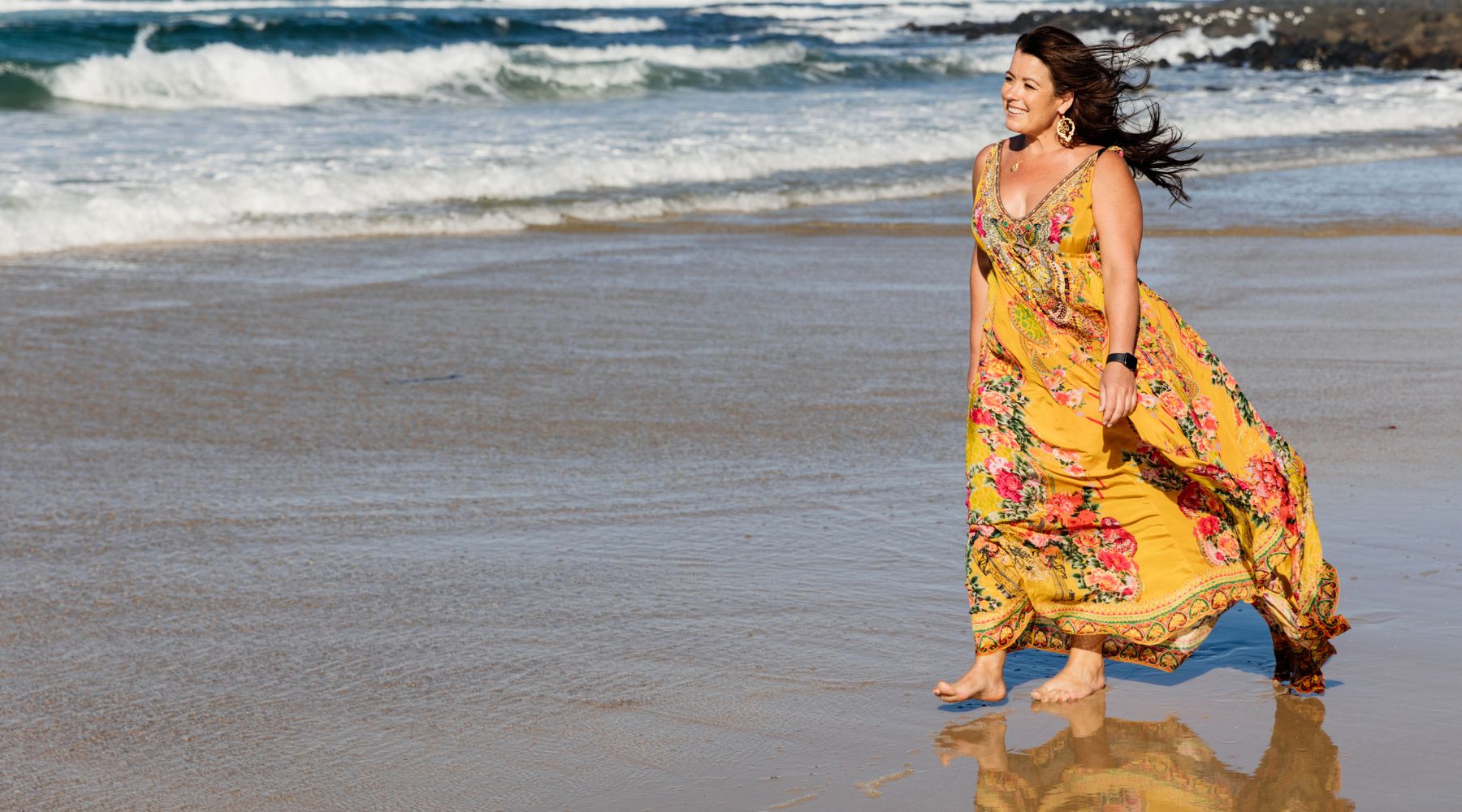 Woman walking on the beach with yellow dress.