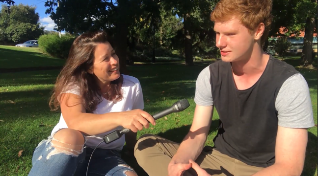 Female participants in a workshop sit in front of a graffiti wall.