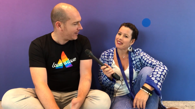 Female participants in a workshop sit in front of a graffiti wall.