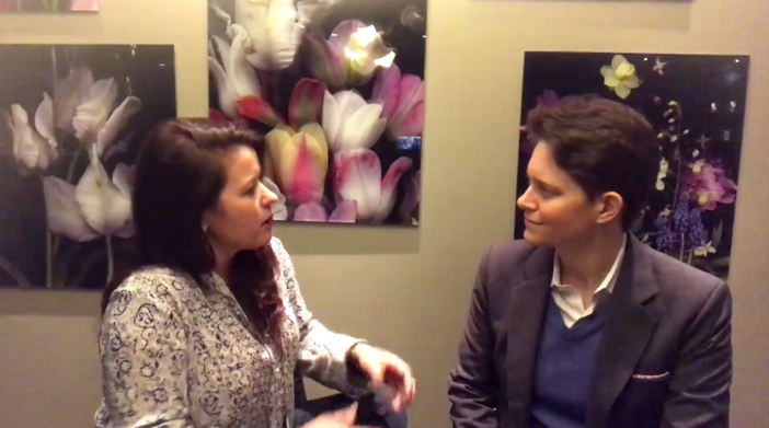 Female participants in a workshop sit in front of a graffiti wall.