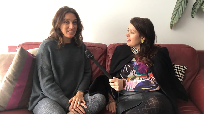 Female participants in a workshop sit in front of a graffiti wall.