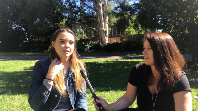 Female participants in a workshop sit in front of a graffiti wall.