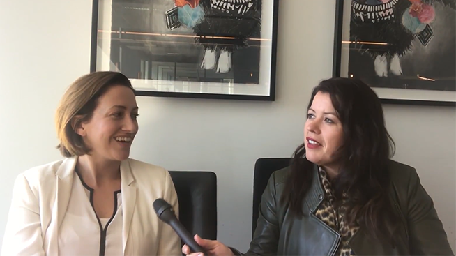 Female participants in a workshop sit in front of a graffiti wall.