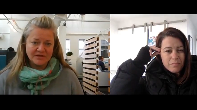 Female participants in a workshop sit in front of a graffiti wall.