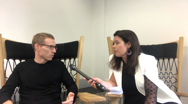 Female participants in a workshop sit in front of a graffiti wall.