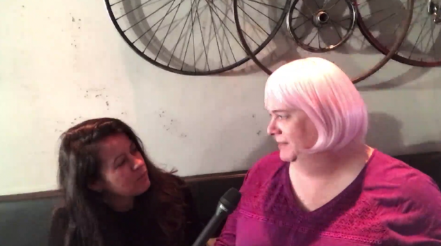 Female participants in a workshop sit in front of a graffiti wall.