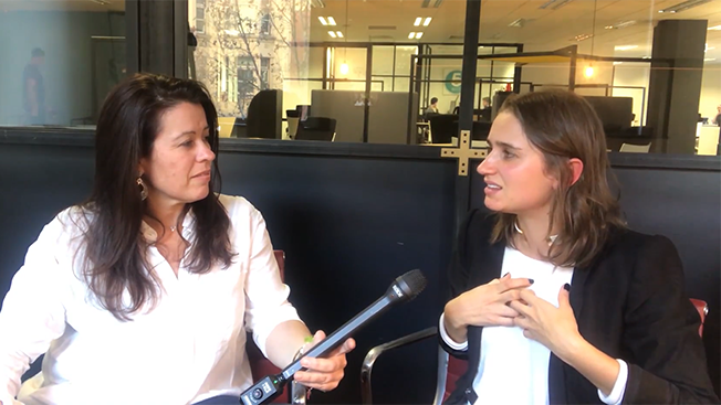Female participants in a workshop sit in front of a graffiti wall.