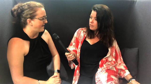 Female participants in a workshop sit in front of a graffiti wall.