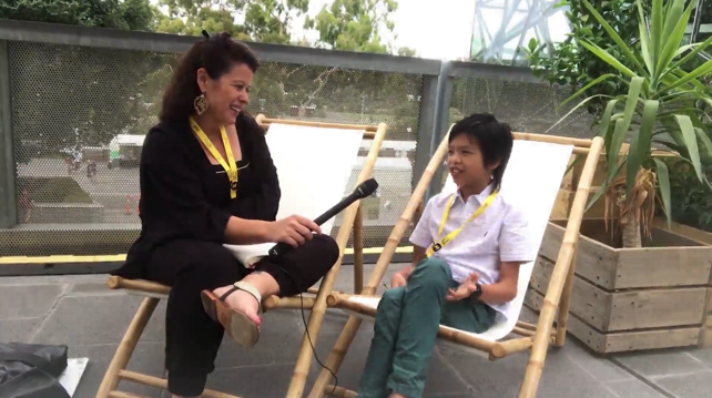 Female participants in a workshop sit in front of a graffiti wall.