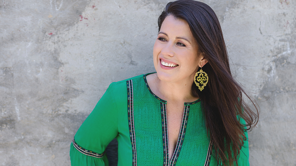 Female participants in a workshop sit in front of a graffiti wall.