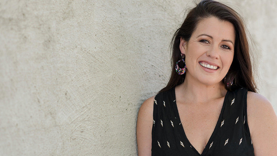 Female participants in a workshop sit in front of a graffiti wall.