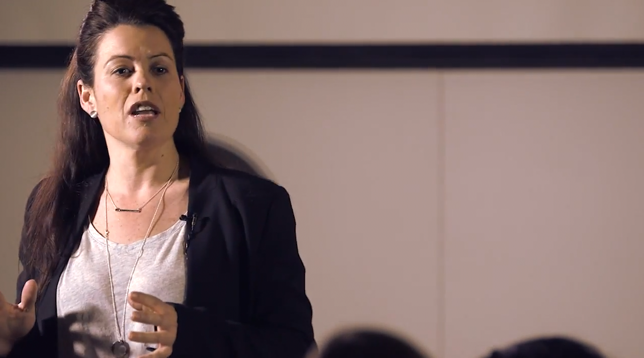 Female participants in a workshop sit in front of a graffiti wall.