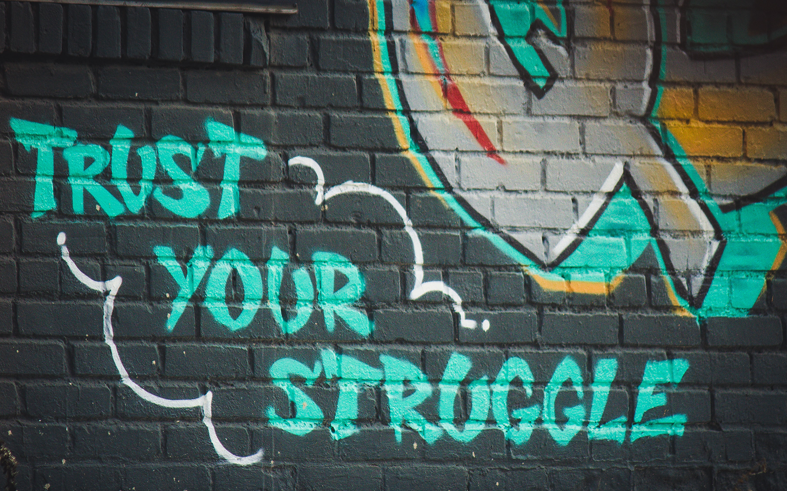 Female participants in a workshop sit in front of a graffiti wall.