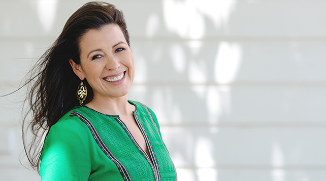 Female participants in a workshop sit in front of a graffiti wall.
