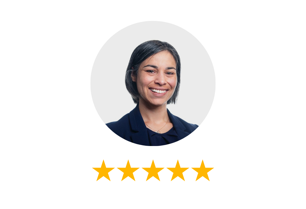 Woman is smiling and wearing a dark navy suit. 5 stars are displayed below her.