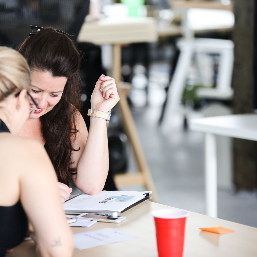 Two women are brainstorming together in a workshop setting.