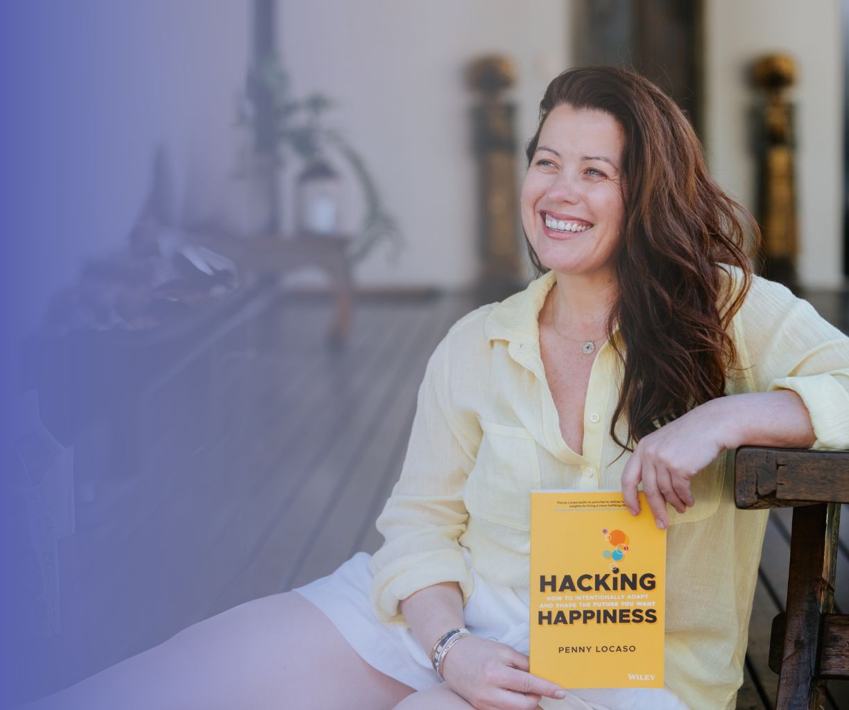 Woman sitting, smiling and holding a book she authored.
