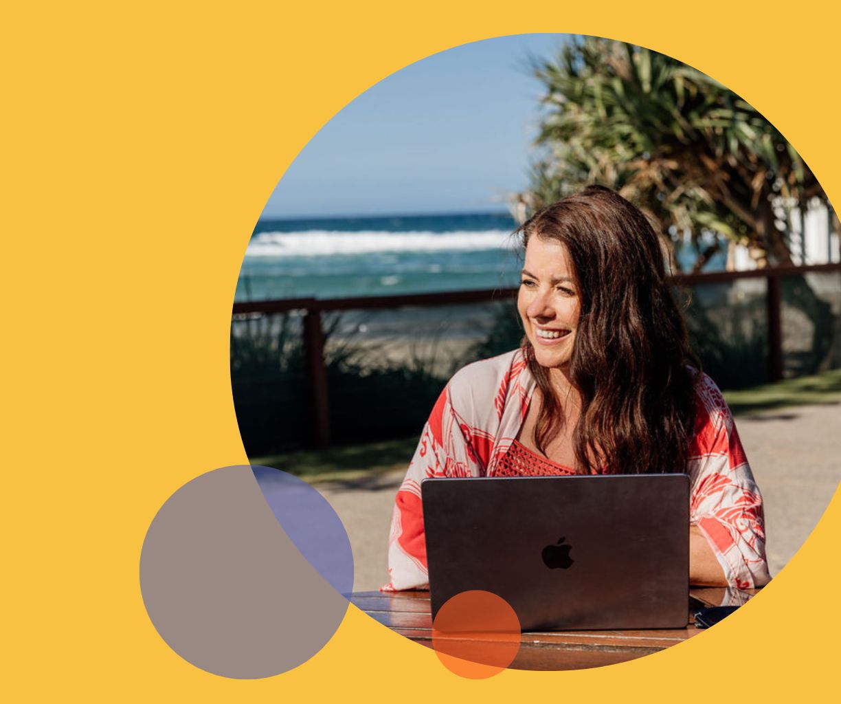 Woman is working on her laptop by the beach.