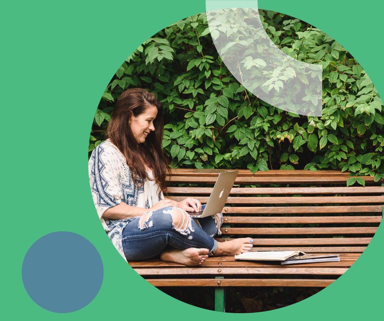 Woman is working on her laptop on a park bench.
