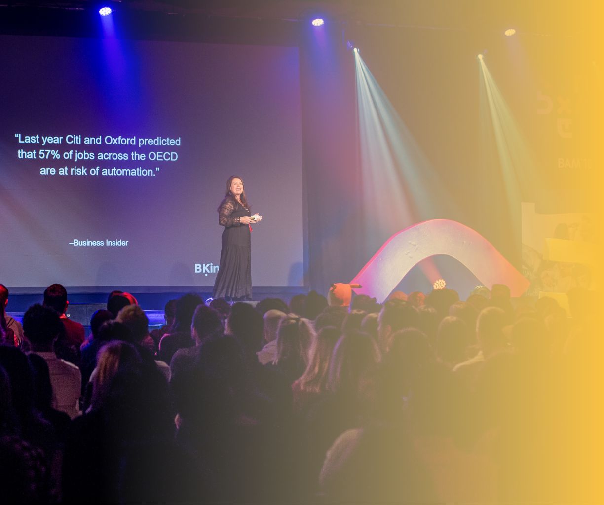 Woman speaking on stage in front of a large audience.