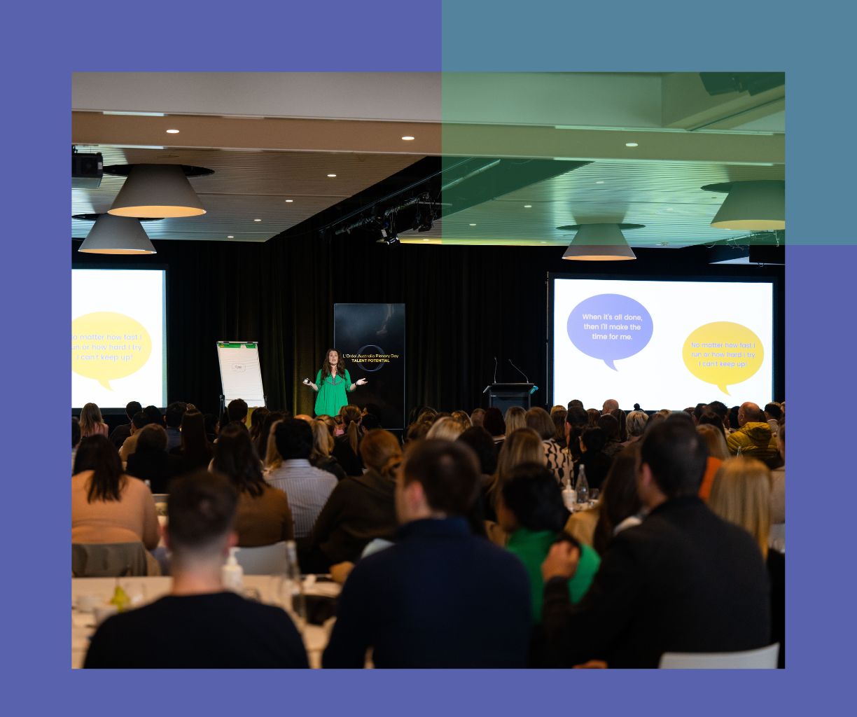 Woman in green is speaking in front of a large audience with slides.