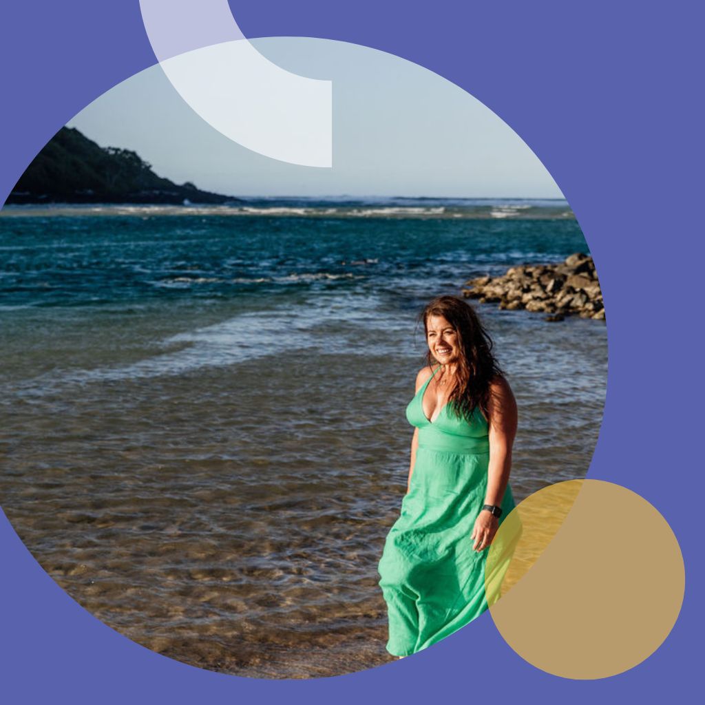 Woman in green dress is walking along the beach.